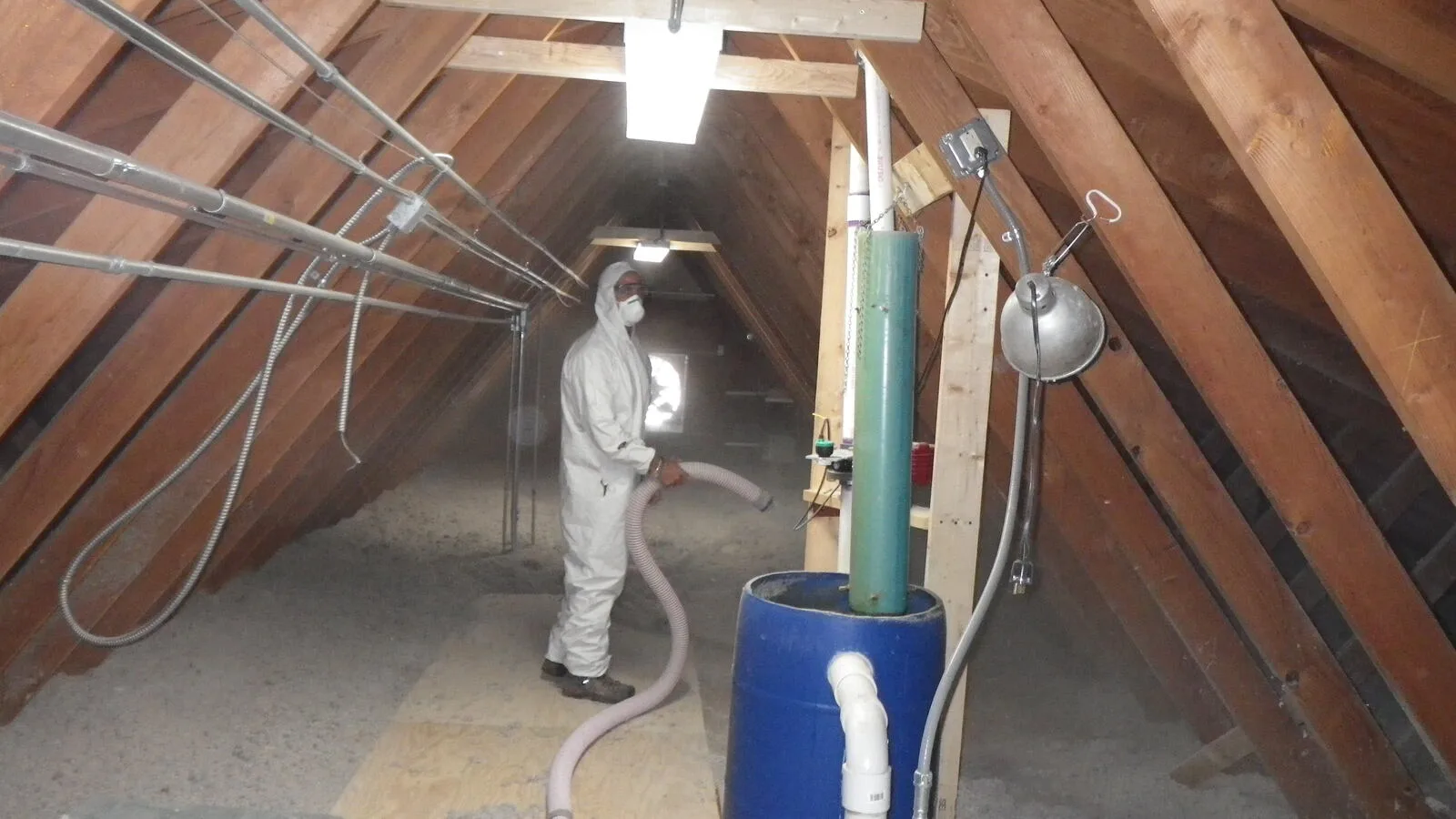 Técnico aplicando aislamiento térmico por insuflado de lana mineral en desván de vivienda
